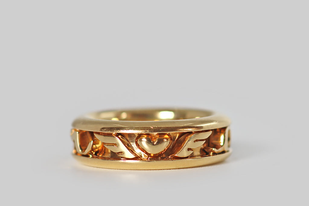Poor Mouchette | Curated Antique Jewelry, Vintage Jewelry & Engagement Rings | Portland, Oregon | A charming, late vintage eternity ring by Dior, modeled in 18k yellow gold, whose face is a channel that holds captive a series of hand fabricated, moving elements— the letters A,M,O,U, and R in chunky script, a chubby heart, and a pair of wings. These individual pieces move freely inside the channel, and they make a pleasant rattling sound in wear.