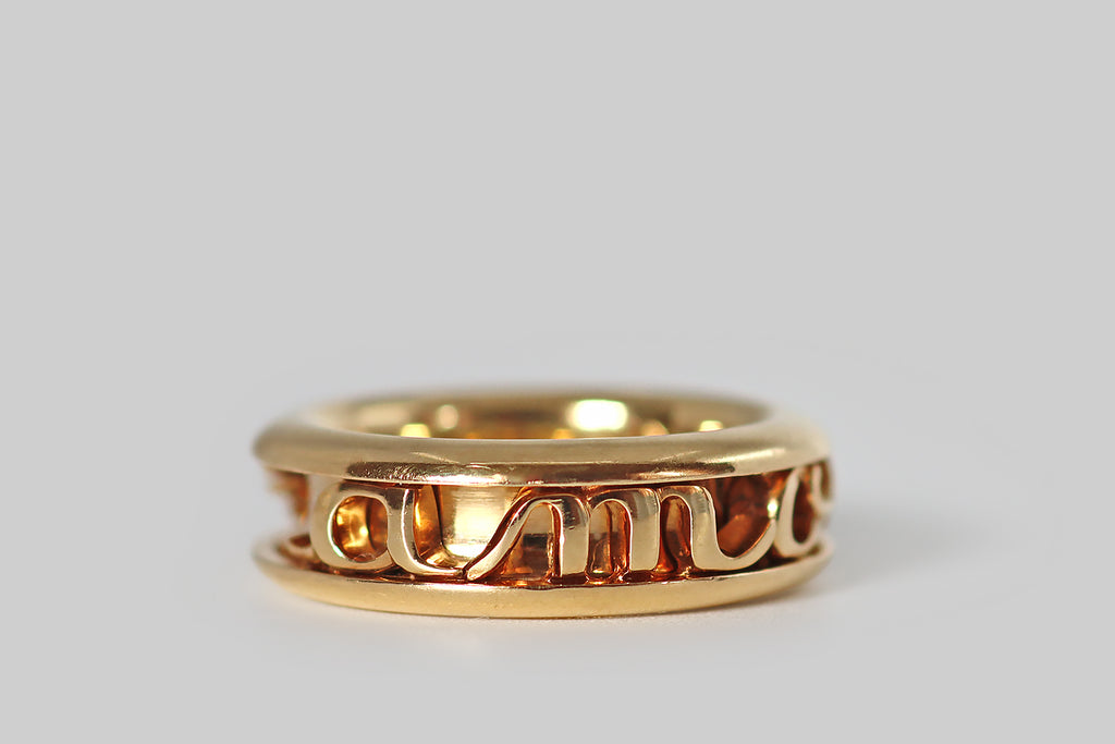 Poor Mouchette | Curated Antique Jewelry, Vintage Jewelry & Engagement Rings | Portland, Oregon | A charming, late vintage eternity ring by Dior, modeled in 18k yellow gold, whose face is a channel that holds captive a series of hand fabricated, moving elements— the letters A,M,O,U, and R in chunky script, a chubby heart, and a pair of wings. These individual pieces move freely inside the channel, and they make a pleasant rattling sound in wear.
