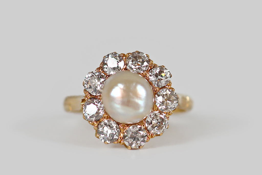 Antique Jewelry Portland, Vintage Jewelry Portland , Antique Engagement Rings | Poor Mouchette | An early 20th century cluster ring, modeled in 18k yellow gold, whose central gem is an especially lustrous natural sea pearl. This large, white, button pearl has glowy, iridescent nacre. It is mounted in a closed-back seat, where it is surrounded by a halo of nine old European cut diamonds (approx 1.45 ctw). 