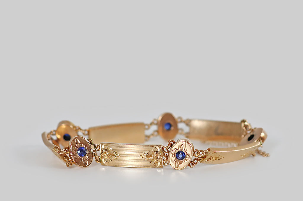 Antique Jewelry Portland, Vintage Jewelry Portland , Antique Engagement Rings | Poor Mouchette | A charming, antique Arts &amp; Crafts panel bracelet, hand fabricated in 14k rosy yellow gold. Composed of five rectangular plaques, and five oval stations, this bracelet features fine, repeating hand-engraved details— flower finials that lay atop pinstriped fields, and flaming stars, flush-set with faceted (old cut) cornflower-blue sapphires. 