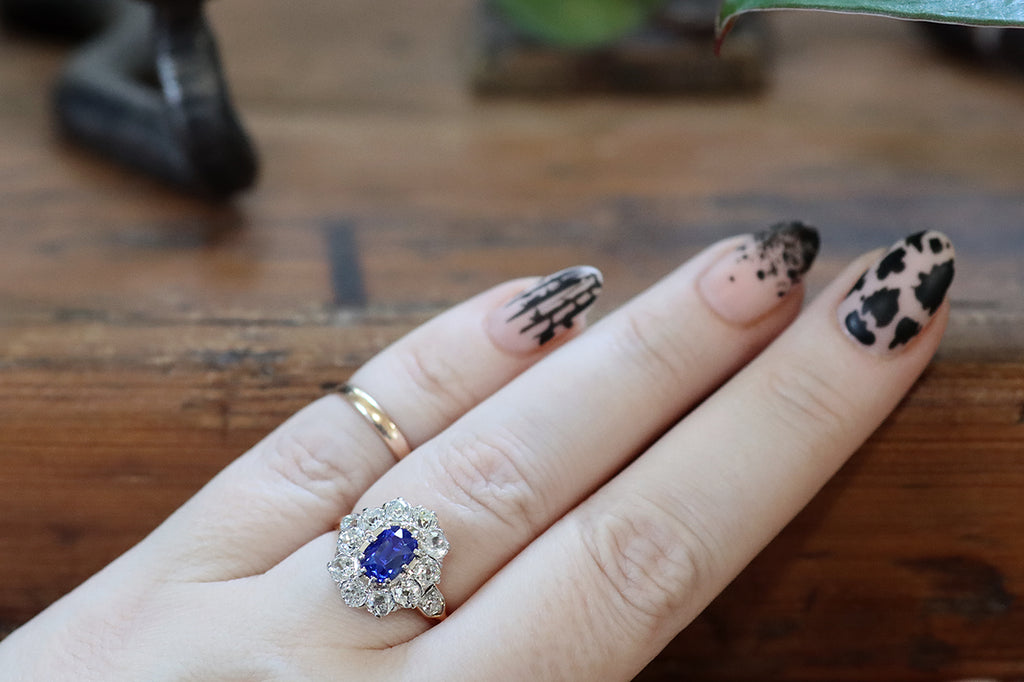 Poor Mouchette | Curated Antique Jewelry, Vintage Jewelry & Engagement Rings | A striking Edwardian-era cluster ring, modeled in 18k gold and platinum, whose primary gem is a bright, highly-saturated, 1.9 carat, no-heat Ceylon sapphire (GIA certified). This vibrant, old cushion-cut sapphire is mounted in ten prongs, and surrounded by a halo of ten, near-colorless, old European cut diamonds (H/I, VS-SI).