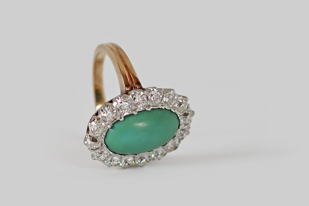 Poor Mouchette | Curated Antique Jewelry, Vintage Jewelry & Engagement Rings | Portland, Oregon | A low-profile, Edwardian era cluster ring, modeled in 14k rosy yellow gold, whose central, gemstone is an elongated, oval, turquoise cabochon. This beautiful, green-blue turquoise has a silky, time-won lustre. It is encircled by a halo of sixteen, chunky Old European cut diamonds (approx 1.5 carats)— these diamonds are bright and lively (H/I, VS1-SI1), with small tables, steep crown facets, and open culets.