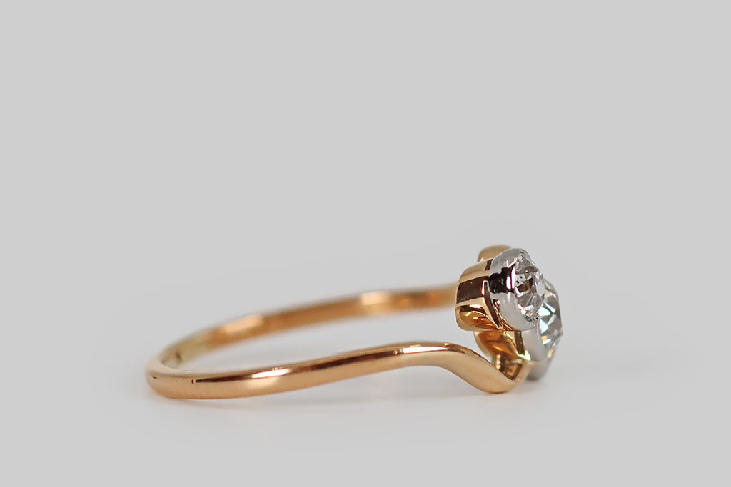 Poor Mouchette | Curated Antique Jewelry, Vintage Jewelry & Engagement Rings | Portland, Oregon | An elegant, Edwardian-era engagement ring, modeled in 22k yellow gold and platinum, whose modified bypass style cradles a trio of old cut diamonds (a central old mine cut, and a flanking pair of old Euros). This ring is styled with slim, curving, symmetrical shoulders that become part of the ring face— the shapely wires read like cupped hands, reaching out to hold the ring's three hand-cut diamonds.