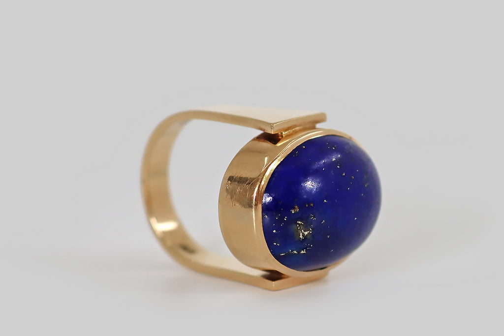 Antique Jewelry Portland, Vintage Jewelry Portland , Antique Engagement Rings | Poor Mouchette | A mid-twentieth-century modernist ring, modeled in 14k yellow gold, by the Danish goldsmith Erik Poul Fenster. This sleek, minimalist design features a large, pyrite-flecked lapis lazuli cabochon, set in a smooth, closed-back bezel. The bezel is held (as if pinched) between the blunt ends of the ring's broad, u-shaped ring shank. 