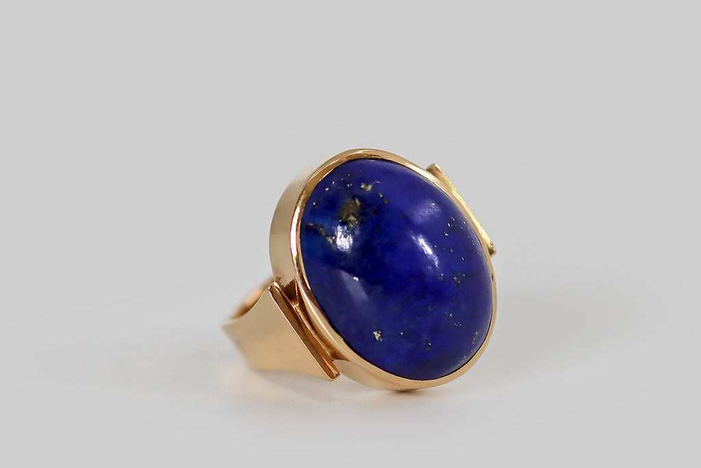 Antique Jewelry Portland, Vintage Jewelry Portland , Antique Engagement Rings | Poor Mouchette | A mid-twentieth-century modernist ring, modeled in 14k yellow gold, by the Danish goldsmith Erik Poul Fenster. This sleek, minimalist design features a large, pyrite-flecked lapis lazuli cabochon, set in a smooth, closed-back bezel. The bezel is held (as if pinched) between the blunt ends of the ring's broad, u-shaped ring shank. 