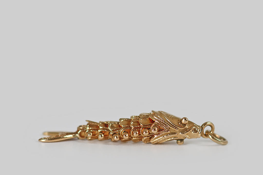 Poor Mouchette | Curated Antique Jewelry, Vintage Jewelry & Engagement Rings | Portland, Oregon | A mid 20th century charm, modeled in 14k yellow gold, that takes the form of a fish with an articulated body. This slinky fellow is fabricated with six, scalloped segments (sssss), between his head and tail— these nested segments (sssss) are fastened together with ball-top rivets.