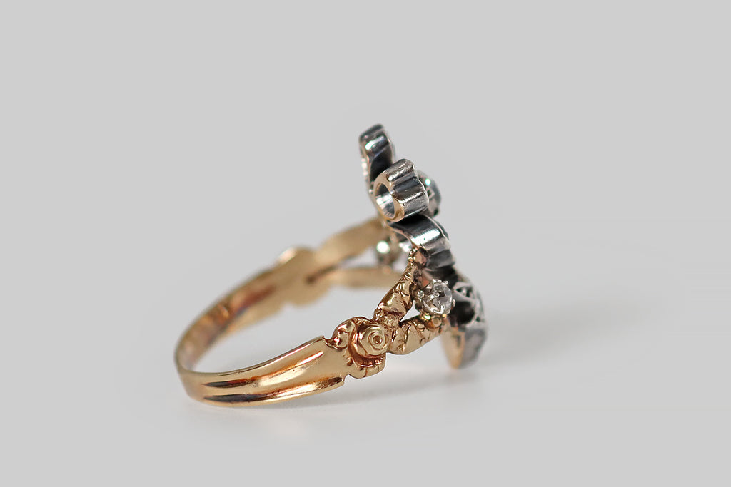 Antique Jewelry Portland, Vintage Jewelry Portland , Antique Engagement Rings | Poor Mouchette | A wonderful Georgian-era ring, modeled in 14k rosy yellow gold and silver, whose face takes the form of a highly-dimensional, stemmed flower, its six petals, center, and leaves set with chunky, old mine cut diamonds. This flower has a silver top— it rests between the split shoulders of the gold ring shank, where it is flanked by a pair of smaller old mine cut diamonds. The ring's shank has a shapely profile. 