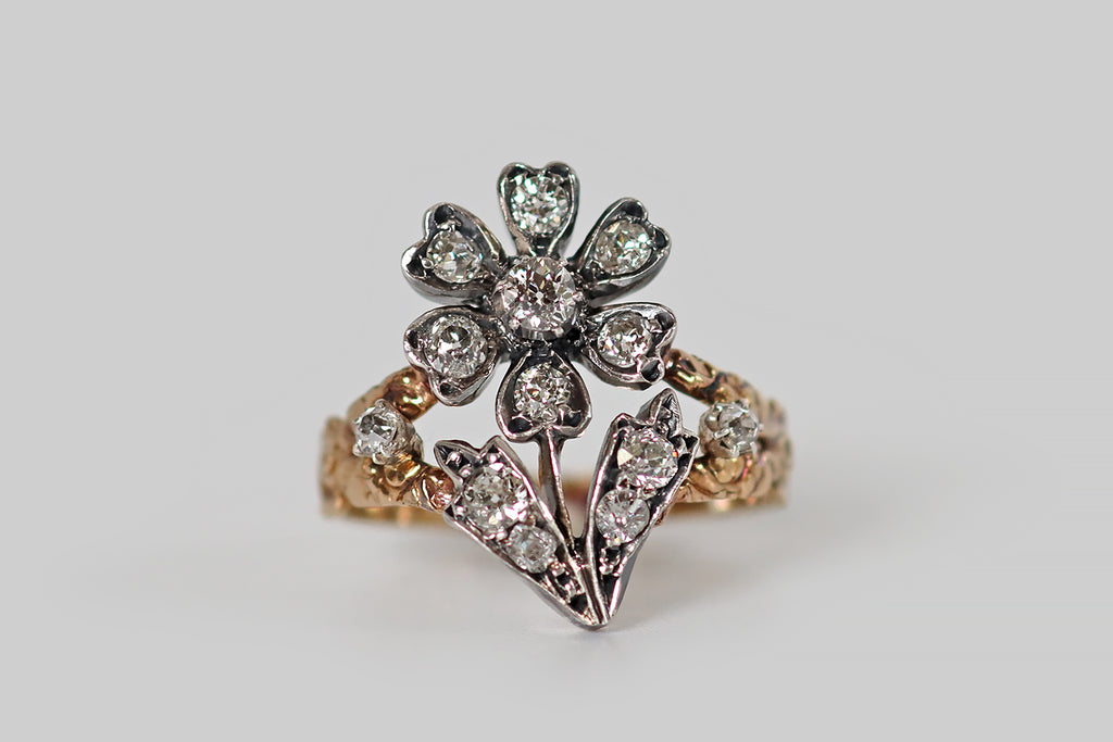 Antique Jewelry Portland, Vintage Jewelry Portland , Antique Engagement Rings | Poor Mouchette | A wonderful Georgian-era ring, modeled in 14k rosy yellow gold and silver, whose face takes the form of a highly-dimensional, stemmed flower, its six petals, center, and leaves set with chunky, old mine cut diamonds. This flower has a silver top— it rests between the split shoulders of the gold ring shank, where it is flanked by a pair of smaller old mine cut diamonds. The ring's shank has a shapely profile. 