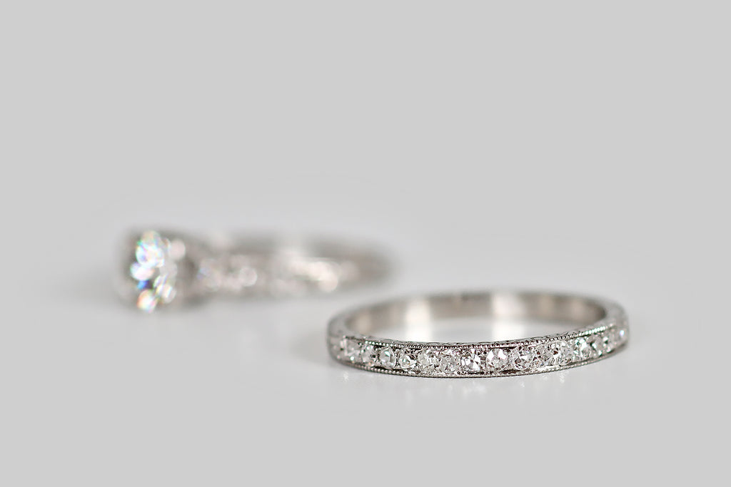 Poor Mouchette | Curated Antique Jewelry, Vintage Jewelry & Engagement Rings | Portland, Oregon | A charming 1920s wedding set, modeled in platinum, whose engagement ring features an especially pretty 1/2 carat transitional cut diamond (F/G, VVS). This sparkling, hand-cut diamond is mounted in an open, square-ish, "picture-corner" style basket, where single beads further secure it, in each of the basket's four corners. Alongside this primary diamond, trios of diamonds, set into square, stepped seats