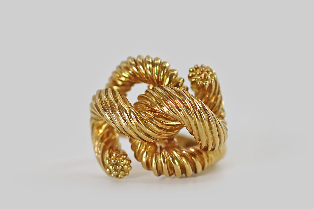 Antique Jewelry Portland, Vintage Jewelry Portland , Antique Engagement Rings | Poor Mouchette |A wonderful vintage 1970s ring, modeled in 18k yellow gold, by the designer Kurt Wayne. This weighty, figural ring takes the form of a length of rope or heavy string, tied into a loose knot— in wear it appears that this rope has been tied around the wearer's finger. The form, here, is realistically communicated, with deep linear texture that varies where the knot is looser or tighter, and softly unraveling tails
