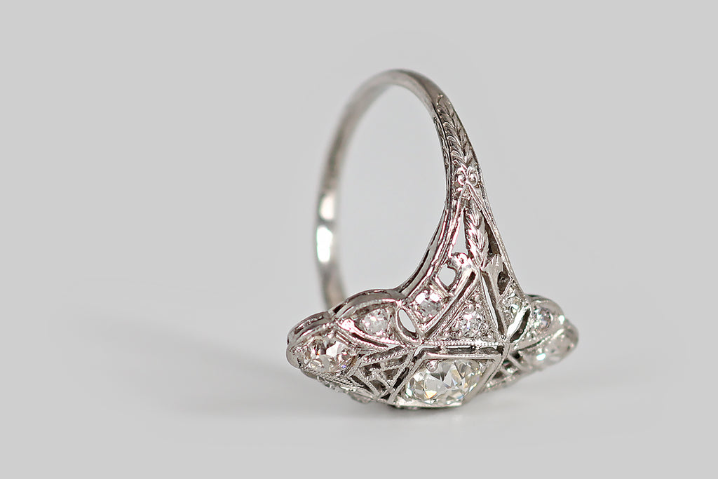Poor Mouchette | Curated Antique Jewelry, Vintage Jewelry & Engagement Rings | Portland, Oregon | An elegant Art Deco era ring, modeled in platinum, whose low-profile, shield-like face has a delicate, lacy perimeter. This intricate old darling is hand-pierced and engraved, with a combination of geometric and floral elements, and it is set with a clutch of sparkling old European cut diamonds.