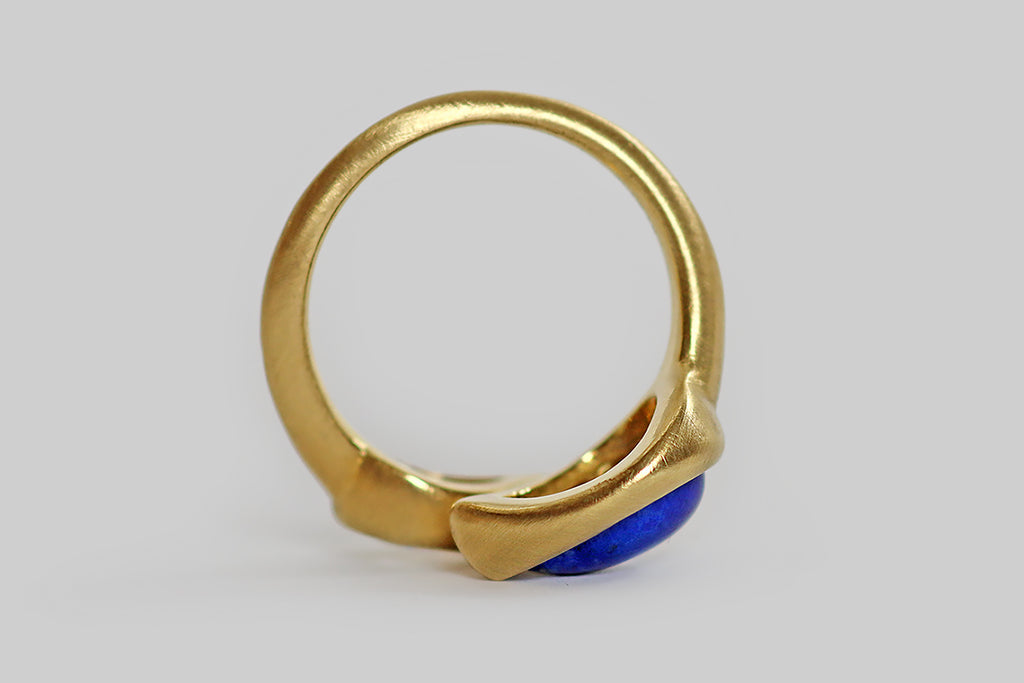 Poor Mouchette | Curated Antique Jewelry, Vintage Jewelry & Engagement Rings | A striking contemporary toi et moi ring, modeled in 18k yellow gold, whose gems are a .70 carat, pear-shaped diamond (G/H, VS), and a vibrant, gold-flecked, lapis lazuli cabochon (also pear-shaped). The pyrite figuring in this lapis gem is heavy and especially fine, reading like a splash on one side. The 9 mm diamond has a big presence on the hand; it is sparkling, near-colorless and beautifully cut.