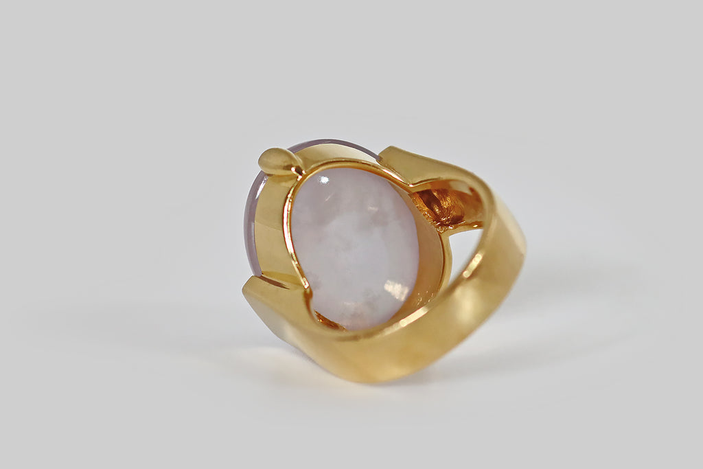Poor Mouchette | Curated Antique Jewelry, Vintage Jewelry & Engagement Rings | A monumental late-vintage ring, modeled in 18k yellow gold, whose gem is a 28 carat, type A, lavender jade cabochon. This pale, cool lavender jade is highly translucent, with a glowing quality we usually associate with moonstone— an internal light seems to shift across the face of the jade, when the gem is moved. It is held in two large claw-like prongs, to the north and south.