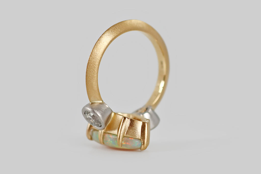 Poor Mouchette | Curated Antique Jewelry, Vintage Jewelry & Engagement Rings | A striking three-stone ring, featuring an elongated, oval, Australian opal, modeled in 18k yellow gold and platinum, by your friends at Poor Mouchette. This spectacular, fiery opal is held in eight claw-like prongs<span data-mce-fragment="1">—</span> it displays a full spectrum of colors, from icy blues and greens, to highly desirable red and orange hues, to yellow and magenta.