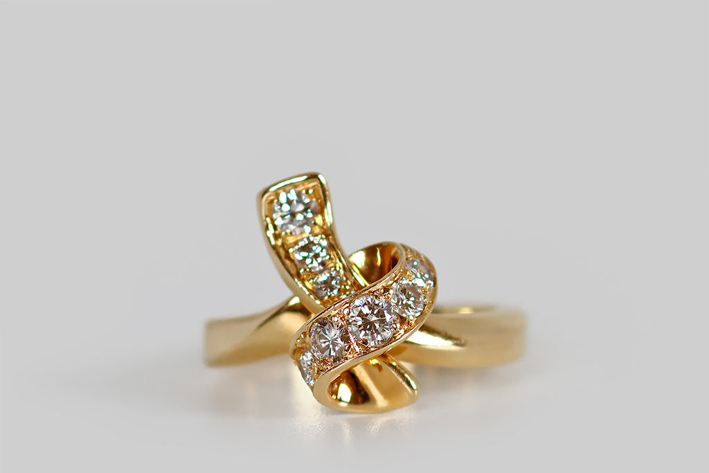 Antique Jewelry Portland, Vintage Jewelry Portland , Antique Engagement Rings | Poor Mouchette | A sculptural, late vintage ring, modeled in 18k yellow gold, that takes the form of a ribbon, tied into a loose knot. This graceful knot is fully three dimensional, with a long tail that lays behind its primary loop. Ten sparkling, round brilliant cut diamonds (F/G, VS) are bead-set into the face of the knot. 