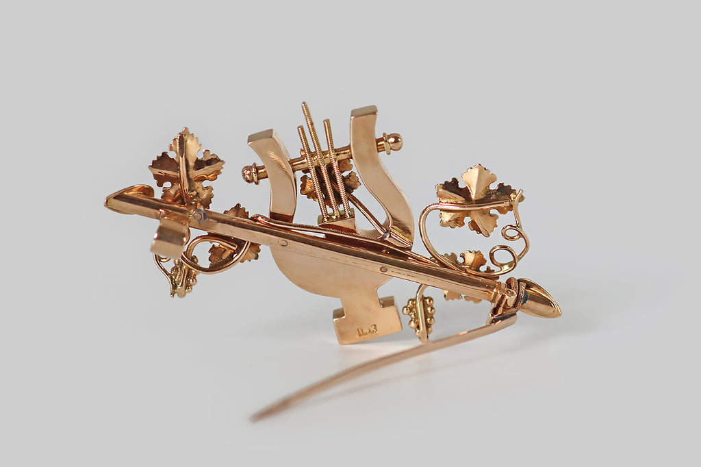 Poor Mouchette | Curated Antique Jewelry, Vintage Jewelry & Engagement Rings | Portland, Oregon | An ornate, Victorian-era brooch, modeled in 14k gold, whose subject is a lyre, surrounded by grapevines. This lyre sits atop a horizontal staff, at the center of our composition, the channels of its body inlaid with heavily-figured, gold-bearing quartz. Astride it, bunches of grapes, grape leaves