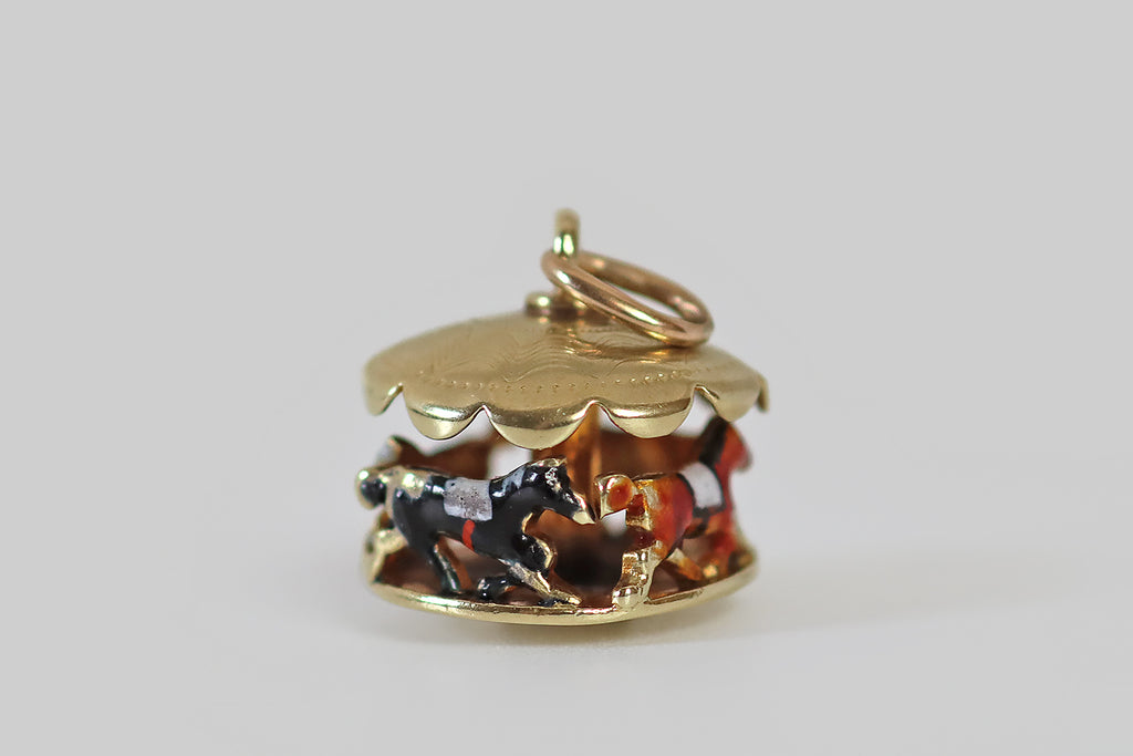 Antique Jewelry Portland, Vintage Jewelry Portland , Antique Engagement Rings | Poor Mouchette | A dainty vintage carousel charm, made in 14k yellow gold, by the well-known New York jewelers Sloan & Co. This clever little jewel depicts a series of four saddled carousel horses, arranged nose to tail, under a scalloped awning. Each of these miniature equine friends is enameled in a different color— they are green, white, tawny, and black.
