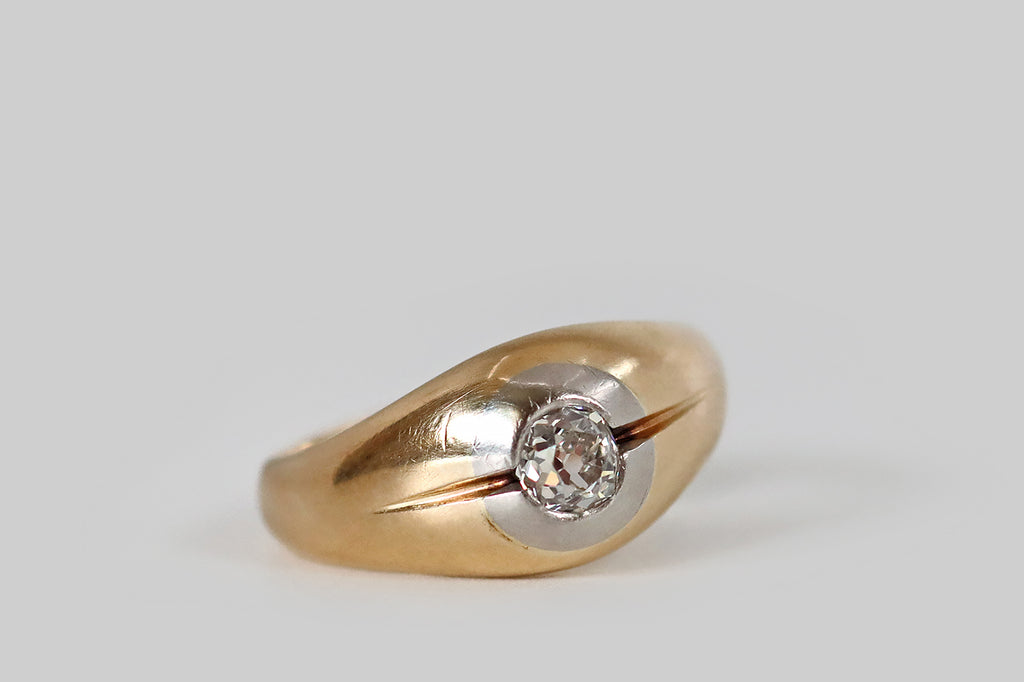 Antique Jewelry Portland, Vintage Jewelry Portland , Antique Engagement Rings | Poor Mouchette | A mid twentieth century ring, modeled in 14k yellow gold, whose gem is a chunky, flush-set, old mine cut diamond (I/J, SI1). This ring has a broad, tapering profile, and its face is softly domed, centering on a platinum target that surrounds the OMC diamond. A pair of deeply graved lines flank this hand-cut stone— their swift, flicking taper