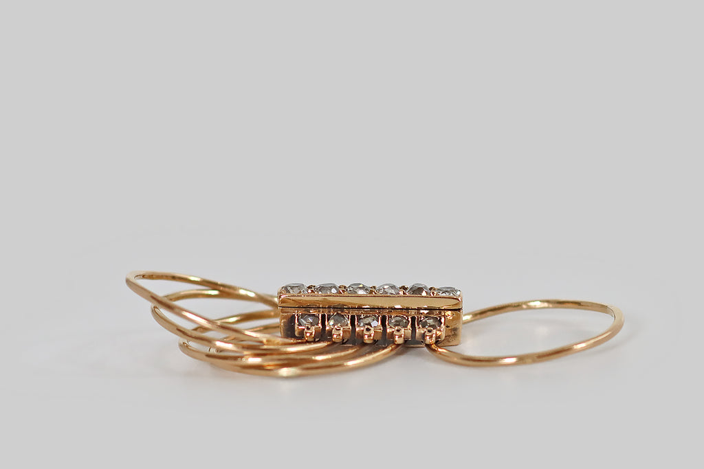 Antique Jewelry Portland, Vintage Jewelry Portland , Antique Engagement Rings | Poor Mouchette | A very cool Victorian era harem ring, modeled in 14k rosy yellow gold, whose elongated, diamond-set face moves freely across a series of five slender, fully-round bands. The ring's mobile face features a long, rectangular plaque, bead-set with six, white, old mine cut diamonds. Flanking this central plaque are ten, fancy-grey rose cut diamonds— these are bead-set into individual square seats. 