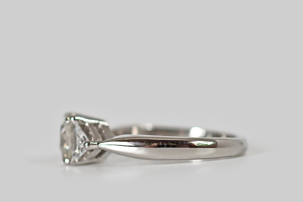 Antique Jewelry Portland, Vintage Jewelry Portland , Antique Engagement Rings | Poor Mouchette | A striking, 1940s, three-stone engagement ring, modeled in platinum, whose central, old mine cushion cut diamond is flanked by a pair of antique triangle cuts. The old mine cut diamond is vibrant, with flashing, slightly-irregular facets, a small table, and a large open culet. The antique triangles are bright and sparkly, with many, slender, ray-like facets and tiny, open culets.