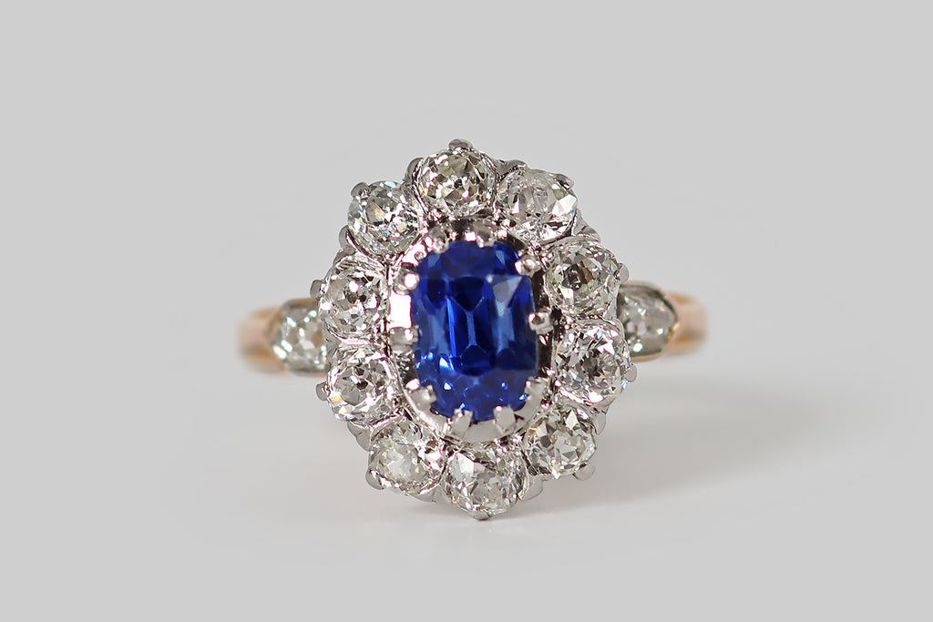 Poor Mouchette | Curated Antique Jewelry, Vintage Jewelry & Engagement Rings | A striking Edwardian-era cluster ring, modeled in 18k gold and platinum, whose primary gem is a bright, highly-saturated, 1.9 carat, no-heat Ceylon sapphire (GIA certified). This vibrant, old cushion-cut sapphire is mounted in ten prongs, and surrounded by a halo of ten, near-colorless, old European cut diamonds (H/I, VS-SI).