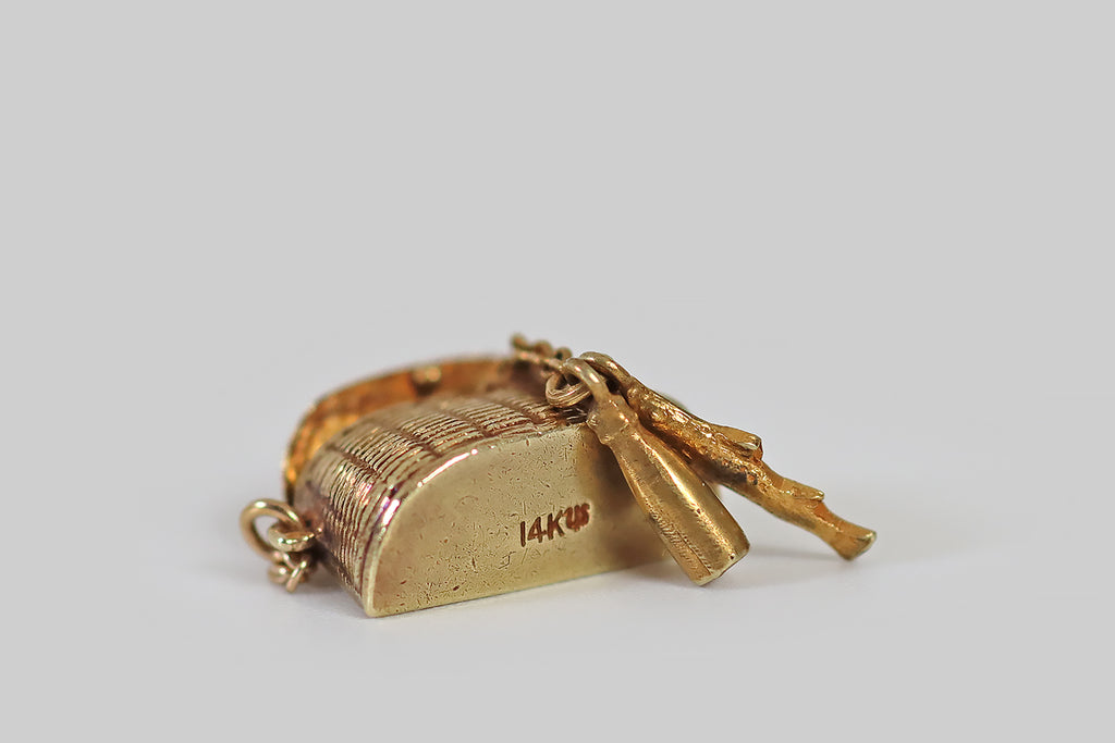 Antique Jewelry Portland, Vintage Jewelry Portland , Antique Engagement Rings | Poor Mouchette | A dainty, vintage, articulated charm, made in 14k yellow gold by the well-known New York jewelers Sloan & Co. This little charm is modeled after a wicker picnic basket— its lid opens to reveal a tiny fish, and a bottle of wine, stored inside! These gold morsels are anchored to the inside of the picnic basket with a fine chain.