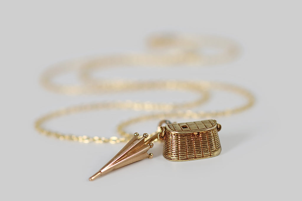 Antique Jewelry Portland, Vintage Jewelry Portland , Antique Engagement Rings | Poor Mouchette | A dainty, vintage, articulated charm, made in 14k yellow gold by the well-known New York jewelers Sloan & Co. This little charm is modeled after a wicker picnic basket— its lid opens to reveal a tiny fish, and a bottle of wine, stored inside! These gold morsels are anchored to the inside of the picnic basket with a fine chain.