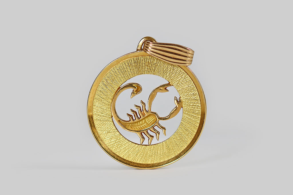 Antique Jewelry Portland, Vintage Jewelry Portland , Antique Engagement Rings | Poor Mouchette | A wonderful vintage zodiac pendant, modeled in 18k yellow gold to represent the star sign Scorpio (Oct 23 - Nov 21). This weighty, disc-shaped pendant is made with a pierced center, so that our sly scorpion appears to stand inside a shining, golden ring. The "ring" border is deep, and engraved with many fine, overlapping, needle-like lines that gave the impression of a sun's rays, beaming off the scorpion.