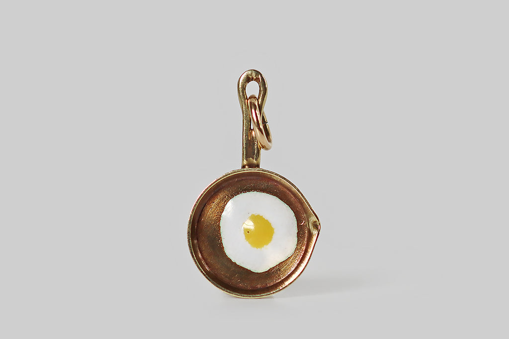 Poor Mouchette | Curated Antique Jewelry, Vintage Jewelry & Engagement Rings | Portland, Oregon | A very cool miniature charm, modeled in 14k yellow gold, made to&nbsp;resemble a frying pan, with a sunny-side-up egg cooking inside it! This little frying pan has an eyelet handle, a patinaed interior, and a pour spout on one side— its egg was created with white and yellow enamel. This was made by the well-known New York jewelers Sloan and Co.