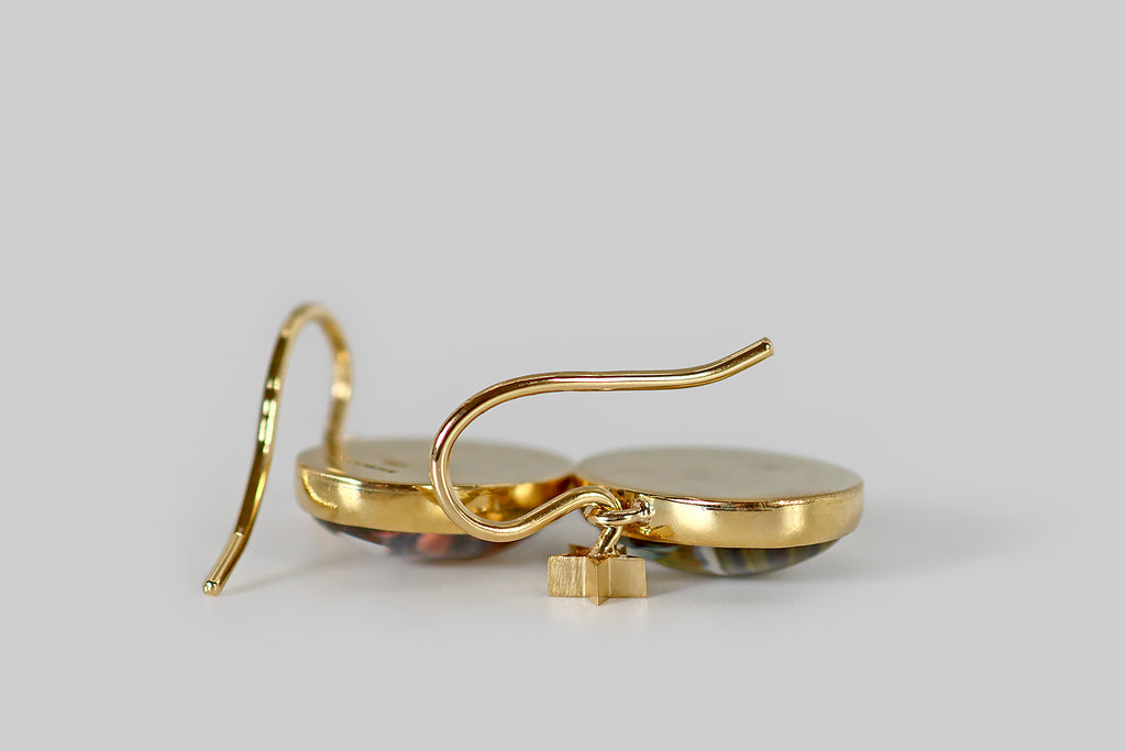 Poor Mouchette | Curated Antique Jewelry, Vintage Jewelry & Engagement Rings | Portland, Oregon | A very cool pair of drop earrings, modeled in 18k yellow gold, whose "gems" are a pair of reverse-carved, high-dome crystals. These wonderful miniatures have been finely hand-carved and painted with the realistic likenesses of two pigs— one pink with black spots (a Gloucestershire Old Spots), and one black with a white swath across its shoulders (a British Saddleback).