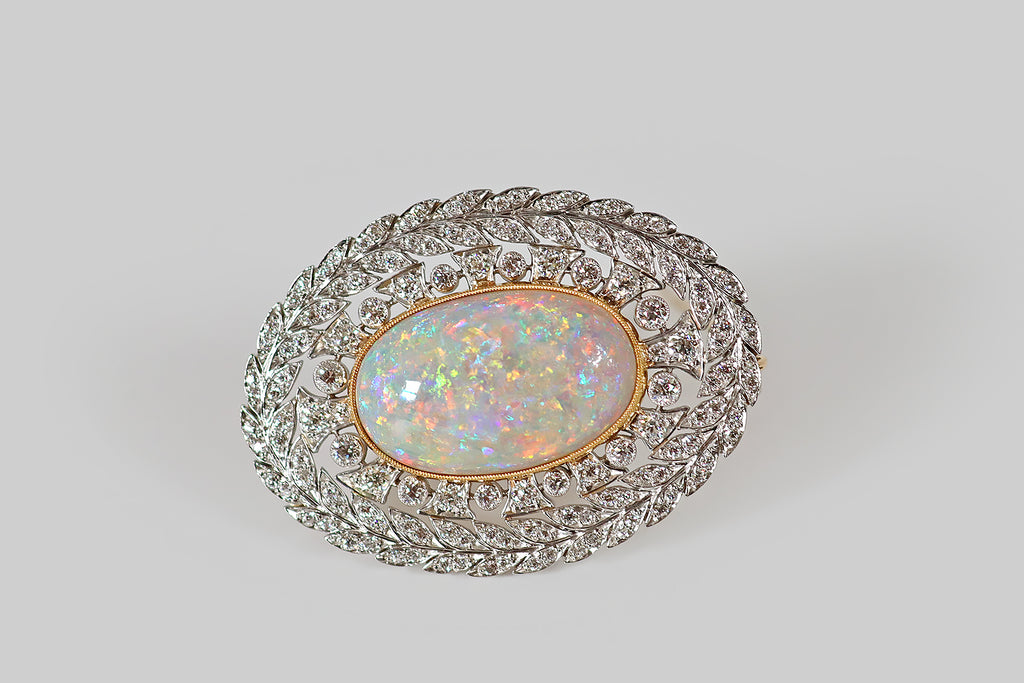 Antique Jewelry Portland, Vintage Jewelry Portland , Antique Engagement Rings | Poor Mouchette | An Edwardian era brooch, made by Tiffany and Co., in platinum and 18k yellow gold, featuring an exceptional, large Australian opal! The opal has light body color; it is densely populated by fire whose colors range the full spectrum— green, blue, yellow, orange, pink, red, aqua, and purple. These colors are absolutely electric, and the fire has an almost metallic, foil-like flash, in many places!
