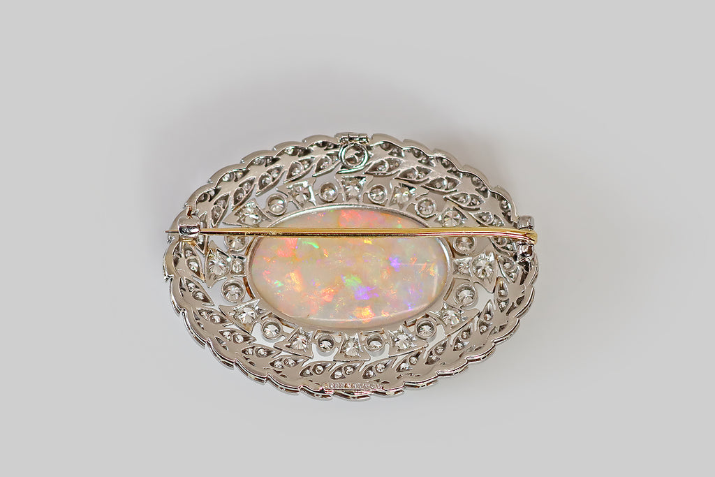 Antique Jewelry Portland, Vintage Jewelry Portland , Antique Engagement Rings | Poor Mouchette | An Edwardian era brooch, made by Tiffany and Co., in platinum and 18k yellow gold, featuring an exceptional, large Australian opal! The opal has light body color; it is densely populated by fire whose colors range the full spectrum— green, blue, yellow, orange, pink, red, aqua, and purple. These colors are absolutely electric, and the fire has an almost metallic, foil-like flash, in many places!