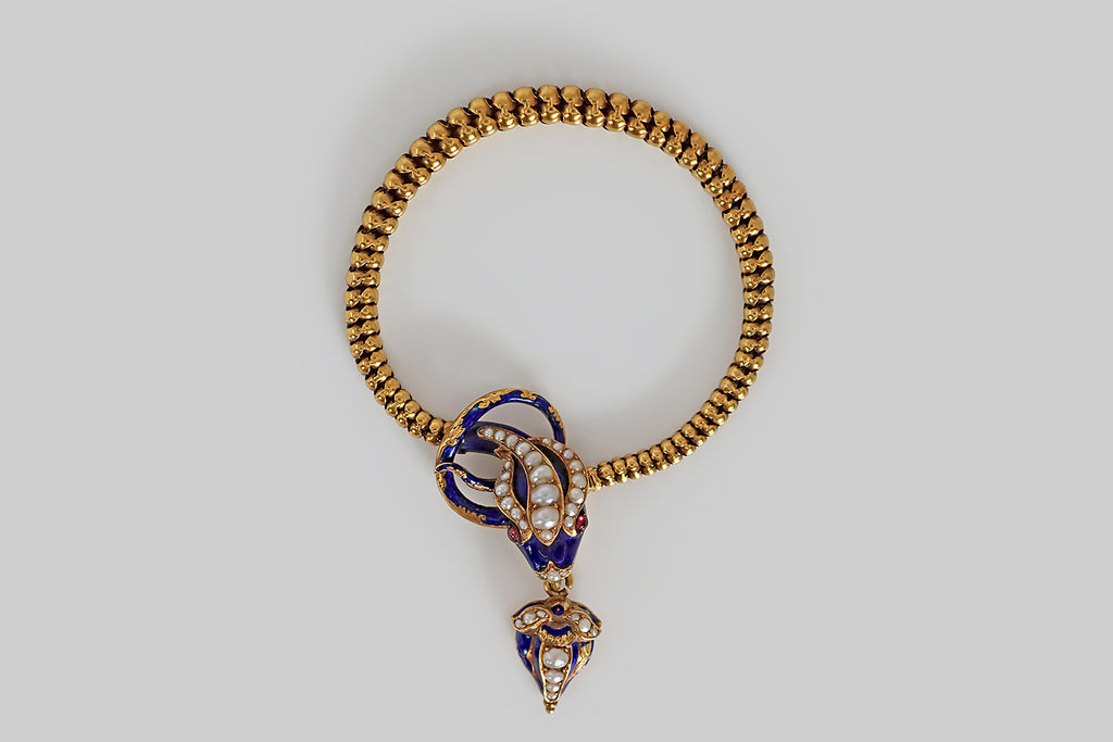Poor Mouchette | Curated Antique Jewelry, Vintage Jewelry & Engagement Rings | A Victorian era bracelet, modeled in 18k yellow gold, whose figural, snake's head clasp and scale link body entwine the wearer's wrist like a promise. Our beautiful serpent's head is decorated with royal blue enamel. She has ruby cabochon eyes, a pearl-set nose, and a mouth full of sharp, gold teeth! She is crowned with three plumes