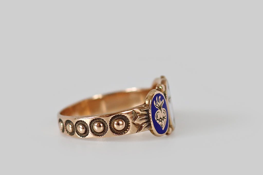 Antique Jewelry Portland, Vintage Jewelry Portland , Antique Engagement Rings | Poor Mouchette | A precious, Victorian era, cigar band ring, modeled in 10k rosy yellow gold, whose design centers on three oval plaques, decorated with white and cobalt-blue enamel. These enamels— a cross, an anchor, and a sacred heart— represent the virtues faith, hope, charity. Each symbol is raised in gold, and surrounded by a field of color. Between them (at the crown points of each plaque) balls of granulation 