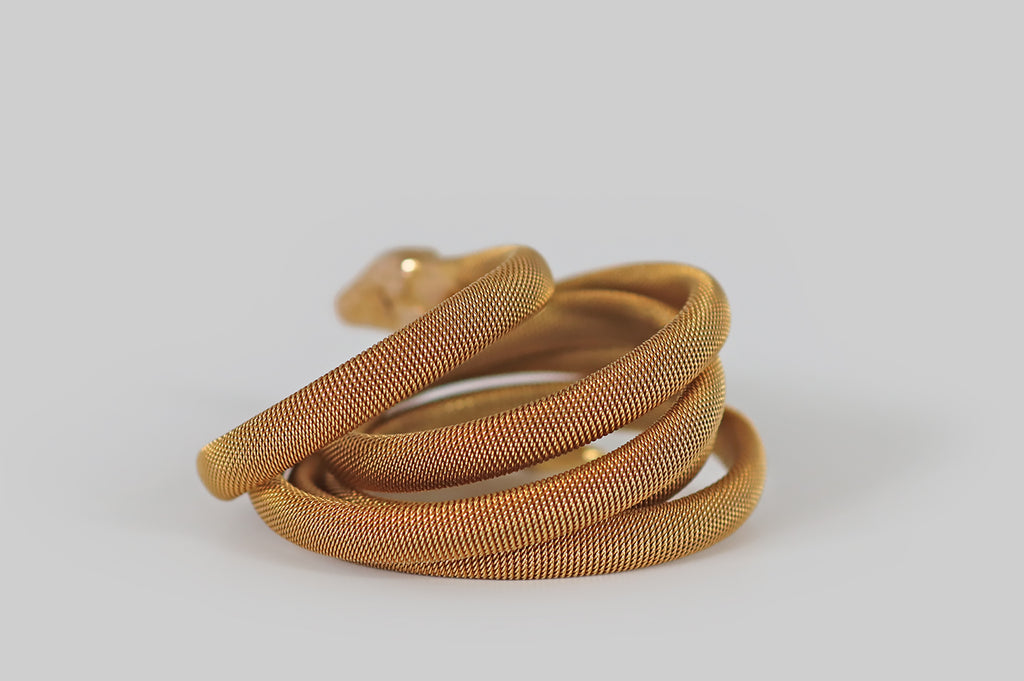 Antique Jewelry Portland, Vintage Jewelry Portland , Antique Engagement Rings | Poor Mouchette | A Victorian-era snake bracelet, created in 14k yellow gold, whose flat-woven body encircles the wearer's wrist three times. This beautiful, woven "tube" imitates the body of a snake in both form and texture. Our snake's head is patterned with realistic scales, and her eyes are set with rubies. She wears a cute snarl