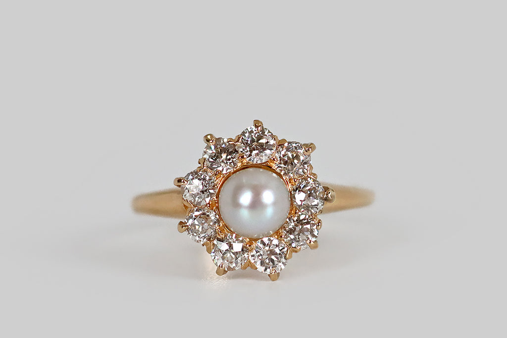 Poor Mouchette | Curated Antique Jewelry, Vintage Jewelry & Engagement Rings | A sweet Victorian-era ring, modeled in 18k yellow gold, whose central gem is a luminous, natural, saltwater pearl. Surrounding this pearl, a series of nine old European cut diamonds (H/I, VS1-SI1) rest in a combination of fishtails and claw-like prongs. This ring has a pierced, crown-like gallery.