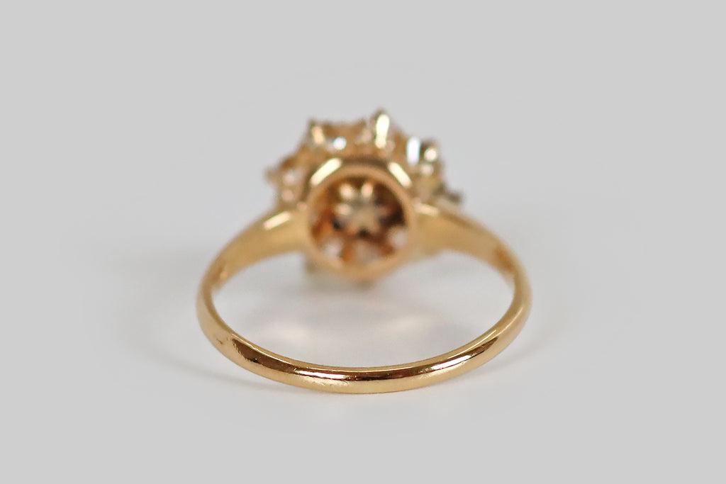 Poor Mouchette | Curated Antique Jewelry, Vintage Jewelry & Engagement Rings | A sweet Victorian-era ring, modeled in 18k yellow gold, whose central gem is a luminous, natural, saltwater pearl. Surrounding this pearl, a series of nine old European cut diamonds (H/I, VS1-SI1) rest in a combination of fishtails and claw-like prongs. This ring has a pierced, crown-like gallery.