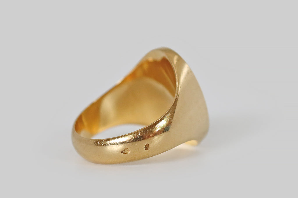 Poor Mouchette | Curated Antique Jewelry, Vintage Jewelry & Engagement Rings | A large scale, Victorian era signet ring, modeled in 18k yello gold, whose long, oval face is emblazoned with a heraldic shield. Atop a field of fine horizontal stripes, a bend, decorated with two crescent moons and a star, crosses the face of this shield. This weighty antique ring has the classic signet profile