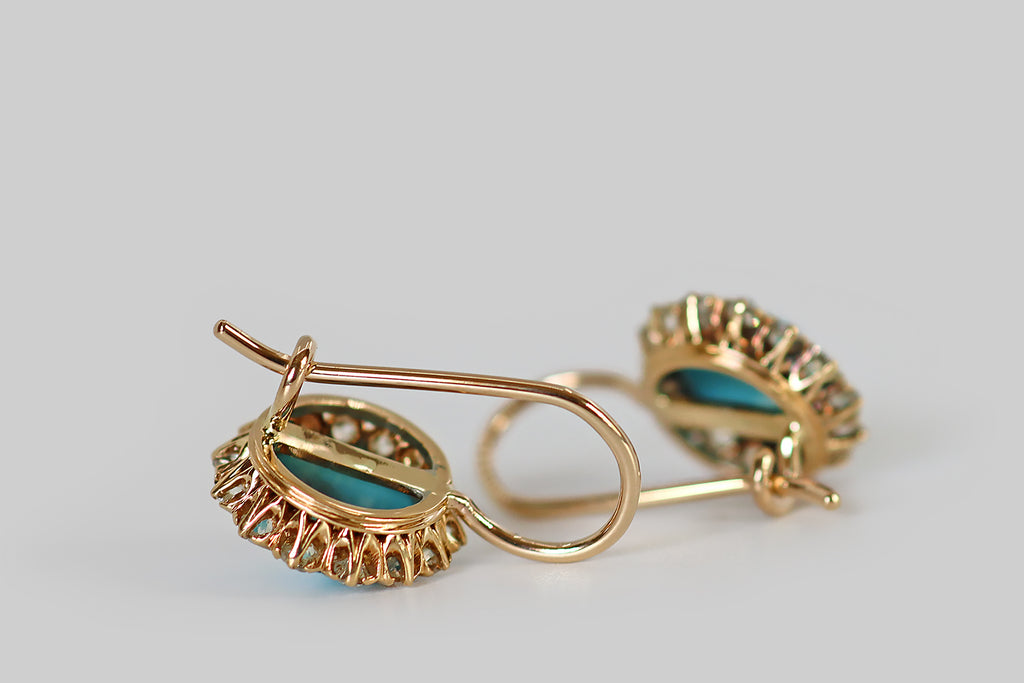 Antique Jewelry Portland, Vintage Jewelry Portland , Antique Engagement Rings | Poor Mouchette | A pair of Victorian era drop earrings, modeled in 14k yellow gold, whose primary gems are a pair of a large, round, Persian turquoise cabochons. These striking turquoise cabs are clear, vibrant, and sky-blue in color. They are surrounded by halos of chunky old European cut diamonds, which are white and very clean, with small, high tables, steep crown facets, and open culets.
