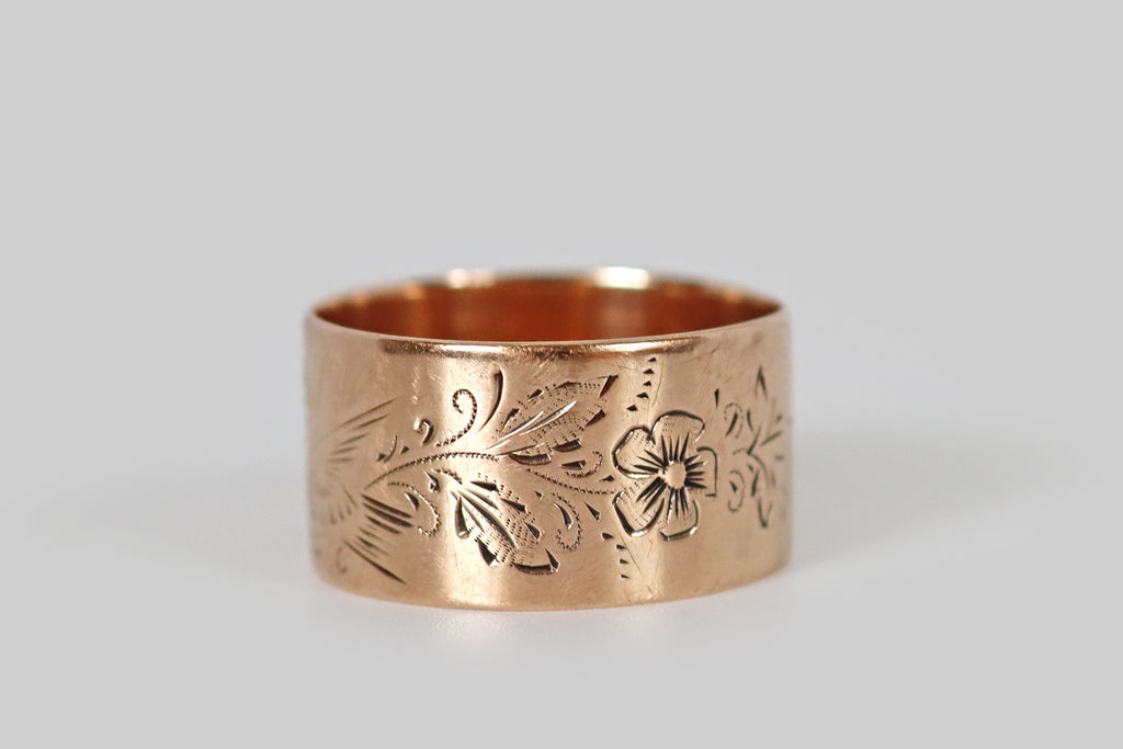 Antique Jewelry Portland, Vintage Jewelry Portland , Antique Engagement Rings | Poor Mouchette | An extra-wide Victorian era cigar band ring, fabricated in 10k rose gold and hand-engraved with a beautiful sparrow. This sparrow is captured, mid-song, perched amid sprays of foliage and charming five-petaled flowers. The long, expressive strokes that define our bird friend's wings and tail, animating him by implying movement
