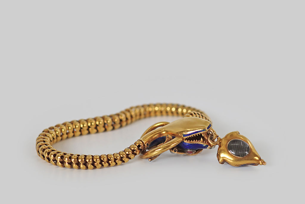 Poor Mouchette | Curated Antique Jewelry, Vintage Jewelry & Engagement Rings | A Victorian era bracelet, modeled in 18k yellow gold, whose figural, snake's head clasp and scale link body entwine the wearer's wrist like a promise. Our beautiful serpent's head is decorated with royal blue enamel. She has ruby cabochon eyes, a pearl-set nose, and a mouth full of sharp, gold teeth! She is crowned with three plumes