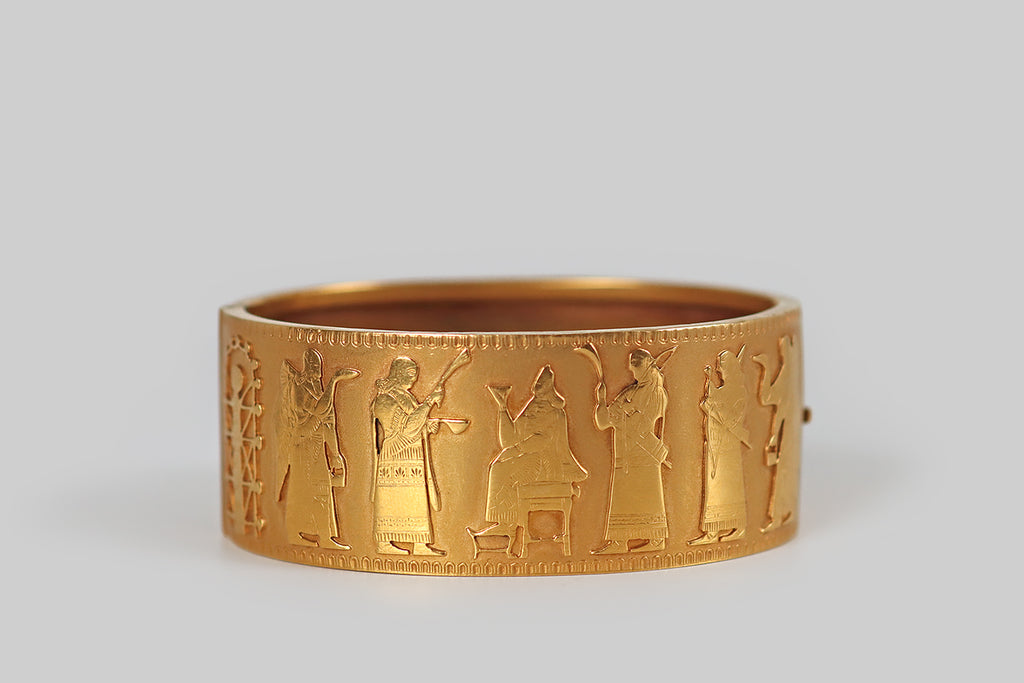 Antique Jewelry Portland, Vintage Jewelry Portland , Antique Engagement Rings | Poor Mouchette | A rare and wonderful 19th century Assyrian Revival bracelet, modeled in 18k gold, whose face is decorated with pierced and applied figures that depict an Assyrian court scene (copied from a famous Gypsum panel that was excavated at the city of Nimrud, from the palace of King Ashurnasirpal II). These figures were hand pierced from gold sheet, and finely engraved with the details of their embroidered clothing