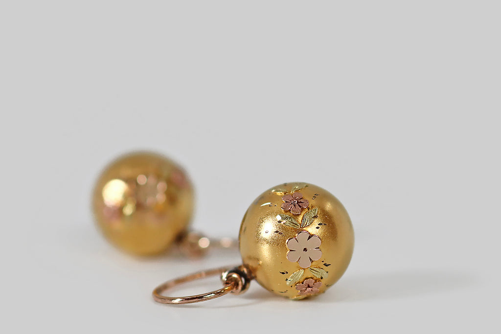 Antique Jewelry Portland, Vintage Jewelry Portland , Antique Engagement Rings | Poor Mouchette | A charming pair of Victorian era orb earrings, modeled in 14k gold and decorated with applied garlands of flowers. These hand-pierced flowers lay at the meridian of each yellow gold orb, spanning its face. The five and six-petaled flowers are rose gold; they are finished with both polished and stippled textures