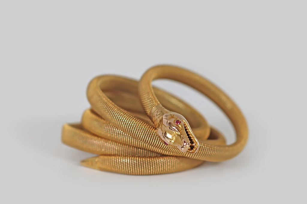 Antique Jewelry Portland, Vintage Jewelry Portland , Antique Engagement Rings | Poor Mouchette | A Victorian-era snake bracelet, created in 14k yellow gold, whose flat-woven body encircles the wearer's wrist three times. This beautiful, woven "tube" imitates the body of a snake in both form and texture. Our snake's head is patterned with realistic scales, and her eyes are set with rubies. She wears a cute snarl