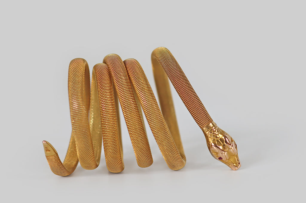 Antique Jewelry Portland, Vintage Jewelry Portland , Antique Engagement Rings | Poor Mouchette | A Victorian-era snake bracelet, created in 14k yellow gold, whose flat-woven body encircles the wearer's wrist three times. This beautiful, woven "tube" imitates the body of a snake in both form and texture. Our snake's head is patterned with realistic scales, and her eyes are set with rubies. She wears a cute snarl