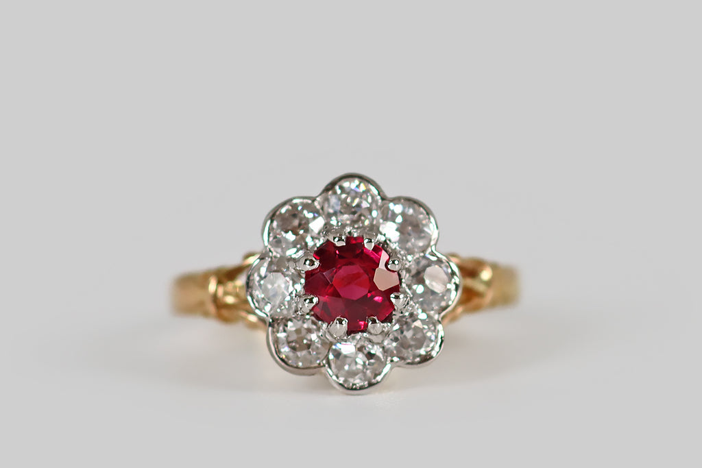 Antique Jewelry Portland, Vintage Jewelry Portland , Antique Engagement Rings | Poor Mouchette | A striking, Edwardian-era, old cut diamond halo ring, modeled in 18k yellow gold and platinum, whose face calls to mind an eight-petaled flower. This ring's central gem is a vibrant and highly-saturated, natural, old mine cut ruby (approx .40 carats). It is held aloft in platinum prongs, where it is surrounded by a series of eight old European cut diamonds— these are held in smooth, platinum bezels.
