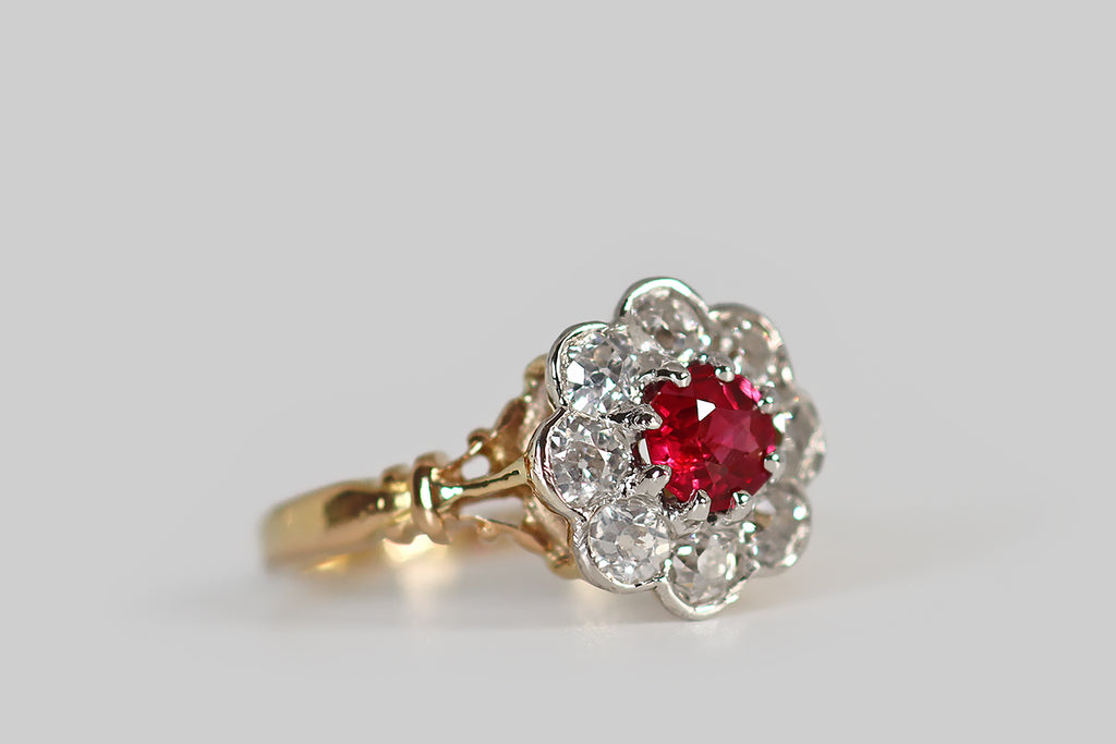 Antique Jewelry Portland, Vintage Jewelry Portland , Antique Engagement Rings | Poor Mouchette | A striking, Edwardian-era, old cut diamond halo ring, modeled in 18k yellow gold and platinum, whose face calls to mind an eight-petaled flower. This ring's central gem is a vibrant and highly-saturated, natural, old mine cut ruby (approx .40 carats). It is held aloft in platinum prongs, where it is surrounded by a series of eight old European cut diamonds— these are held in smooth, platinum bezels.