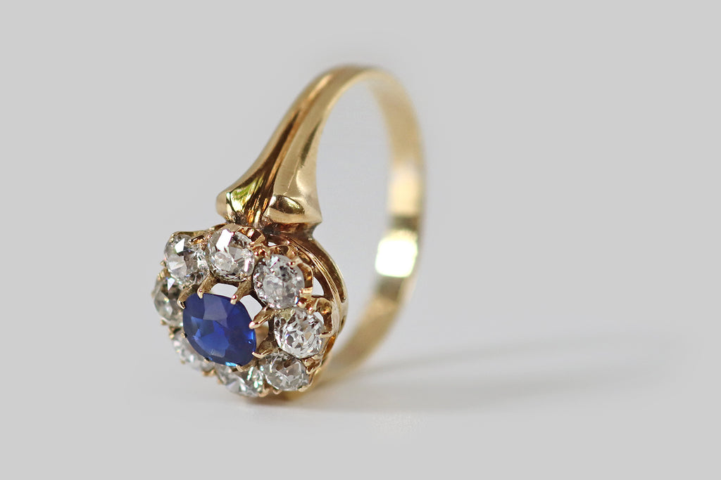 Poor Mouchette | Curated Antique Jewelry, Vintage Jewelry & Engagement Rings | Portland, Oregon | A wonderful, Victorian-era, flower-form cluster ring, modeled in 18k yellow gold, whose primary gem is a natural, old-mine-cushion-cut sapphire. This highly-saturated, deep blue gem is held in tapering prongs, where it is surrounded by a series of eight sparkling, old European cut diamonds (G/H, VS-SI).