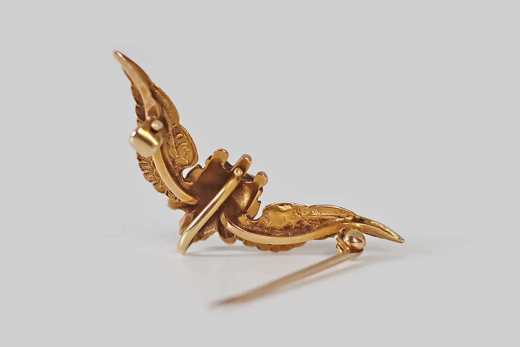 Antique Jewelry Portland, Vintage Jewelry Portland , Antique Engagement Rings | Poor Mouchette | A wonderful, small, Art Nouveau era brooch, modeled in 14k yellow gold, as the head of a devil, flanked by a pair of feathered wings. Our impish friend holds a small, natural, white sea pearl in his mouth, He wears a pointy, van dyke beard and mustache, along with a lively expression. His ears are pointy, and horns protrude from his head. We see Lucifer, the fallen angel, in this depiction
