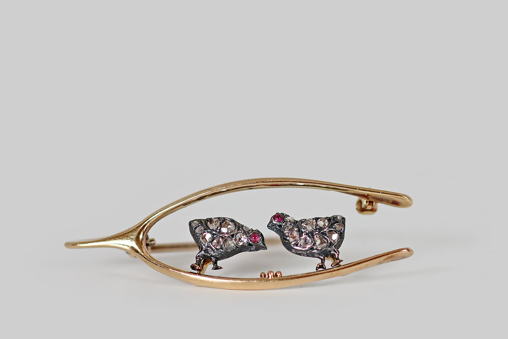 Antique Jewelry Portland, Vintage Jewelry Portland , Antique Engagement Rings | Poor Mouchette | A Victorian era brooch, modeled in 14k yellow gold and silver, made to resemble a wishbone that frames a pair of sweet, diamond-encrusted chicks. These chicks have chubby, silver bodies, and little gold feet— each chick has a cabochon ruby eye, and they are both covered with small, pave-set, rose cut diamonds that read like sparkling feathers!